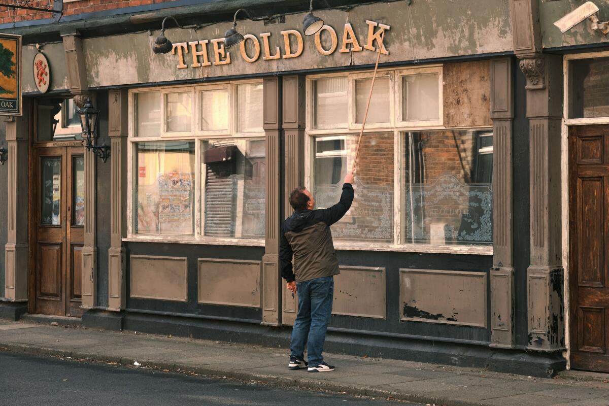 A man works on the sign of a pub.