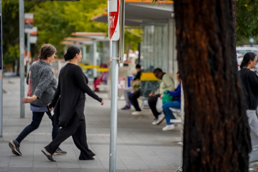 Pedestrians walking down a street near a bus stop in Broadmeadows.