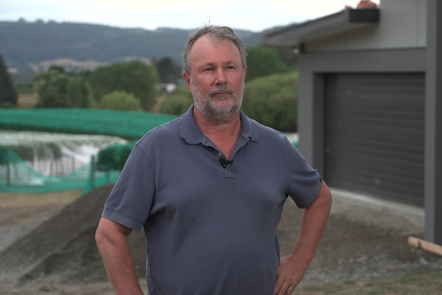 A man stands in front of a house construction site.