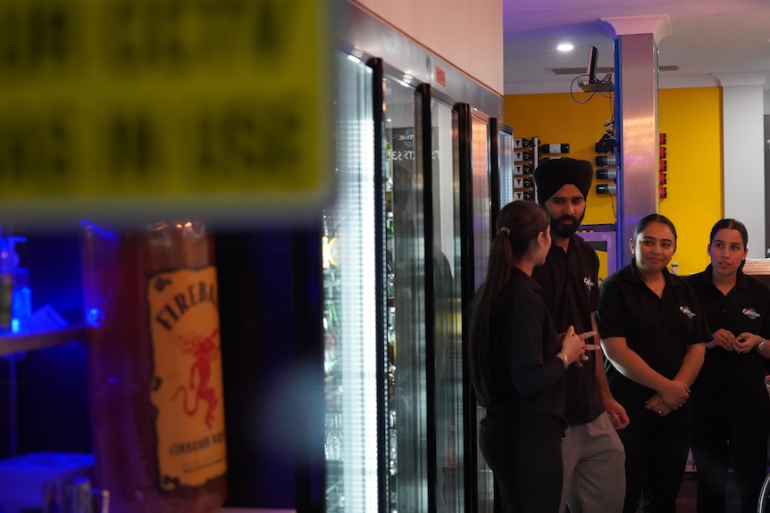 a man wearing a turban talks to staff in a bottle shop