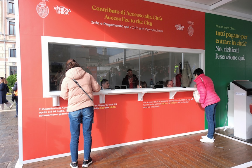 Two women stand at an information booth.