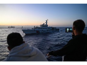 Philippine Coast Guard personnel film a China Coast Guard vessel during a supply mission in the disputed South China Sea on March 5. Photographer: Jam Sta Rosa/AFP/Getty Images