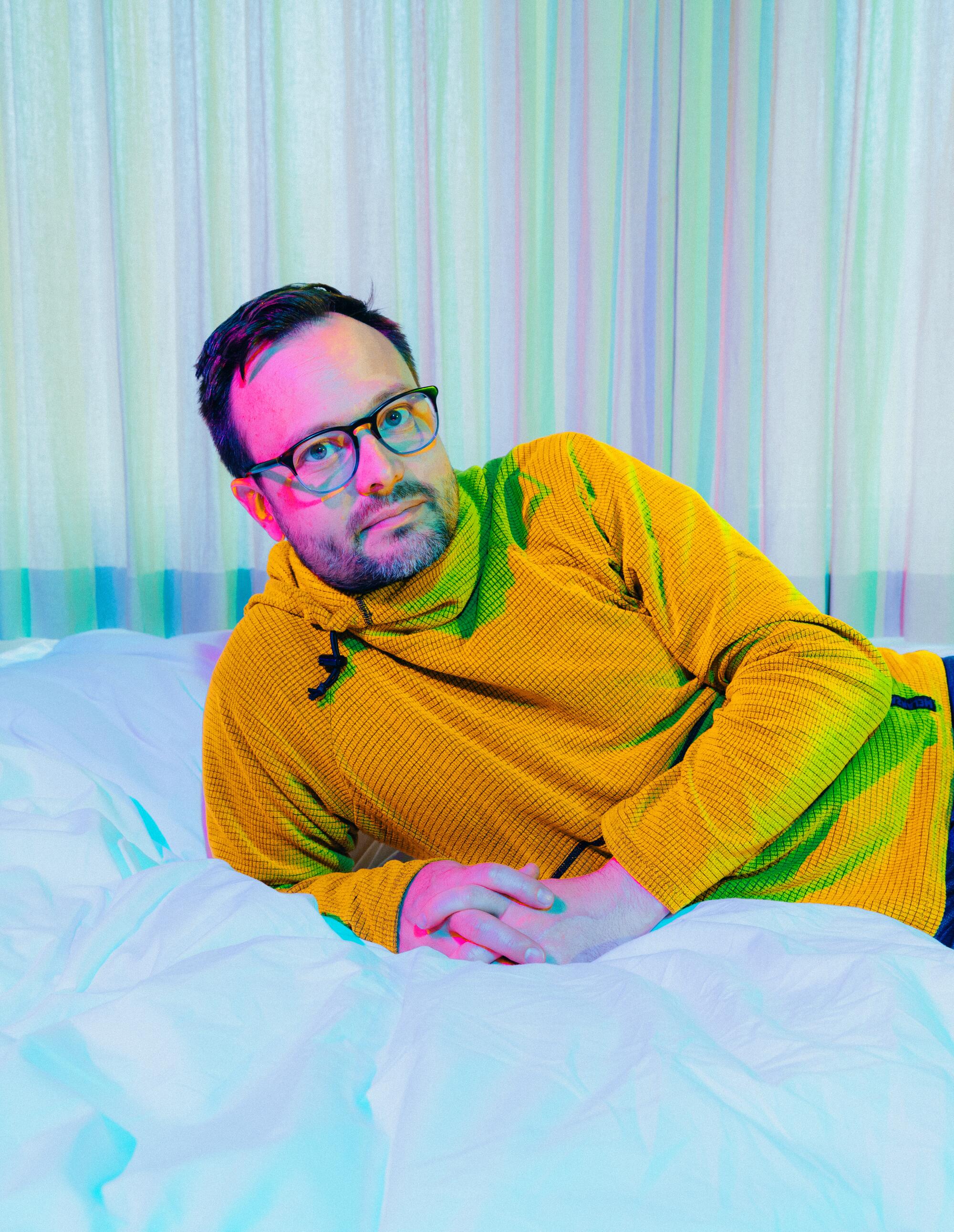 Meow Wolf co-founder Sean Di Ianni reclines on a bed in a Los Angeles hotel room. 