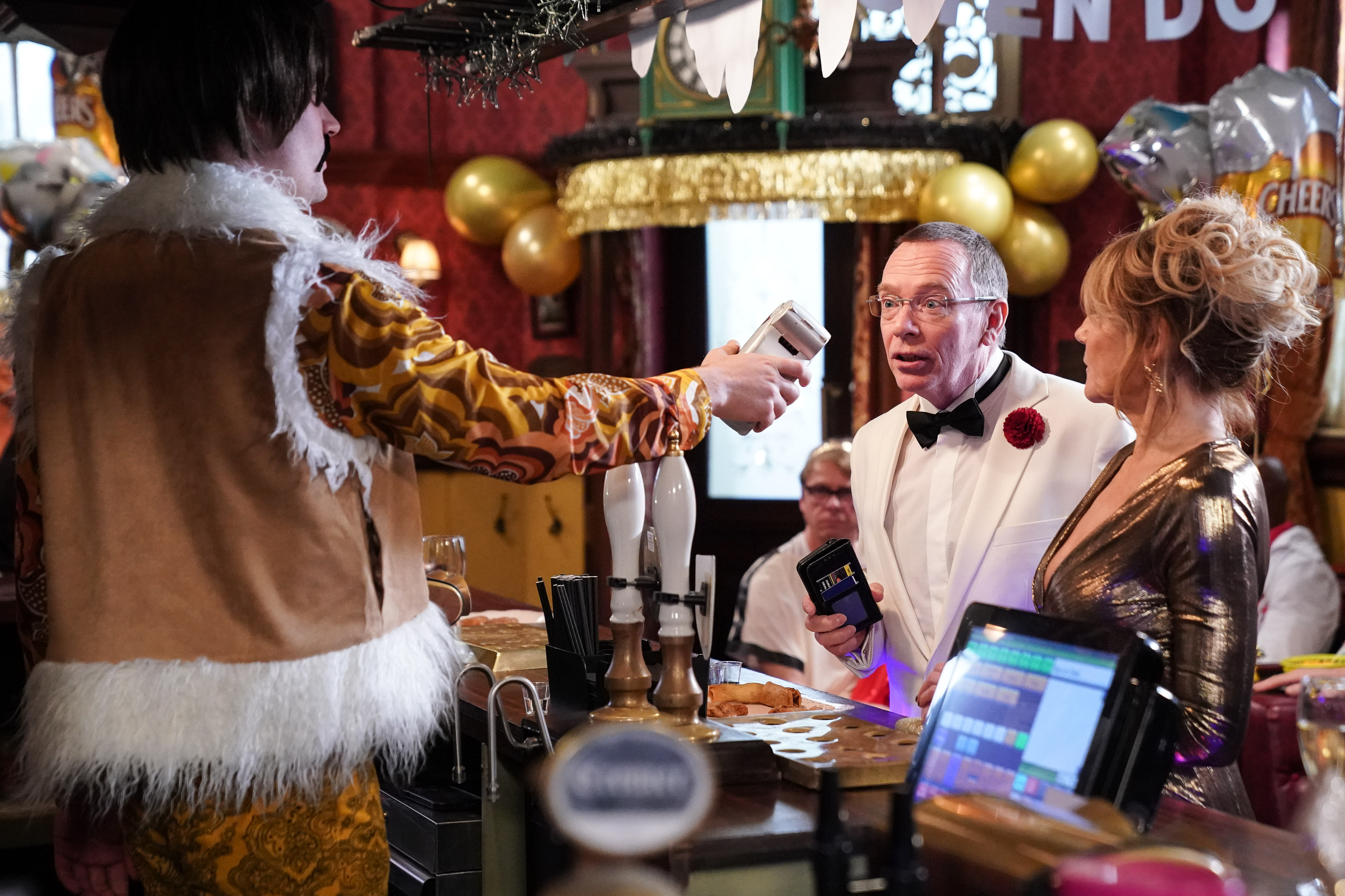 Ian Beale is flanked by Cindy as he seems to have a complaint as he is being served by Johnny Carter