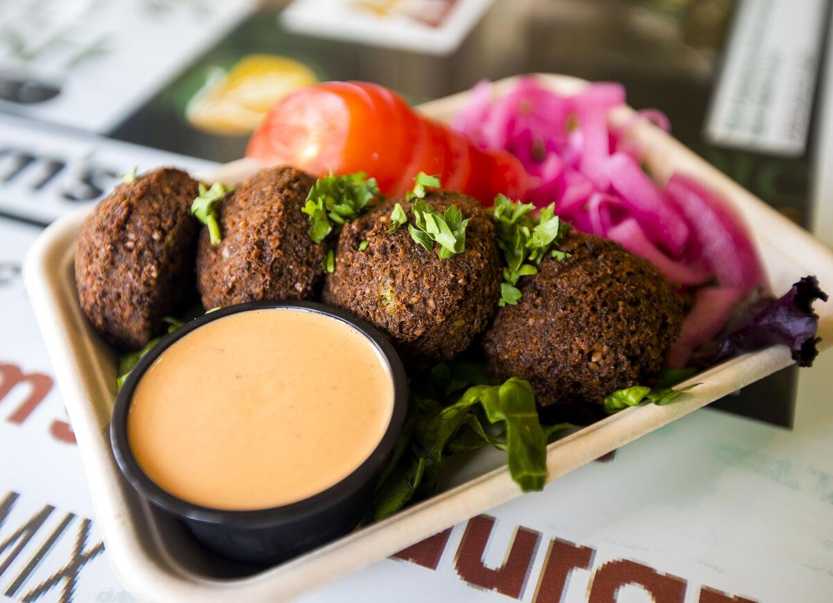 Freshly made falafel with an orange sauce, sliced tomatoes and pickled turnip pieces