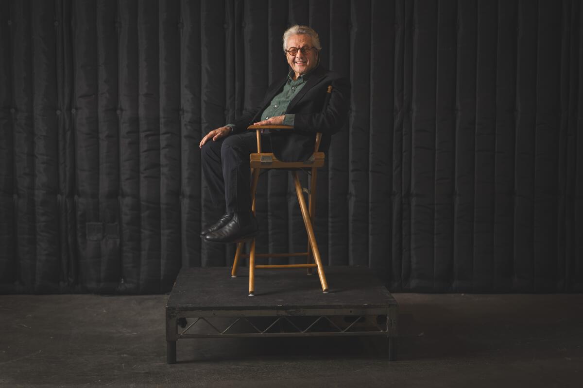 A man in a director's chair smiles.