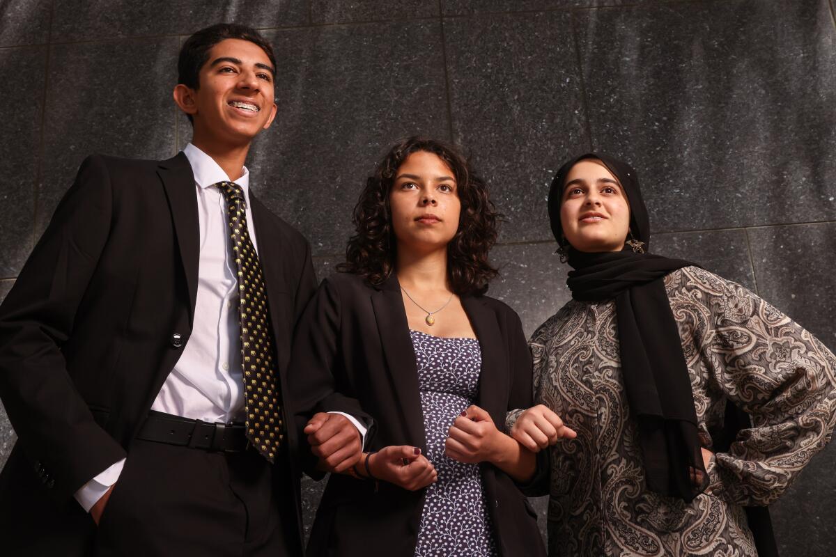 Three youths in formal attire pose for a photograph.