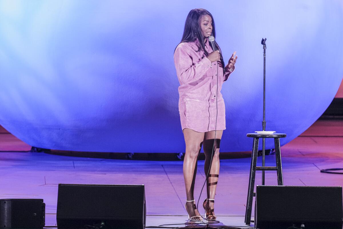 Woman on stage holding a mic and doing stand up