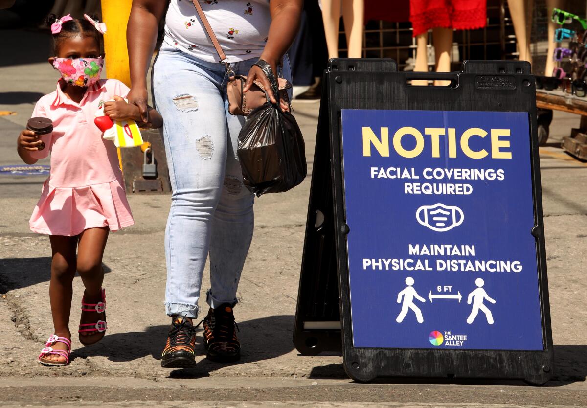  A young shopper, wearing a mask, shops with her mother in downtown Los Angeles in June 2020. 

