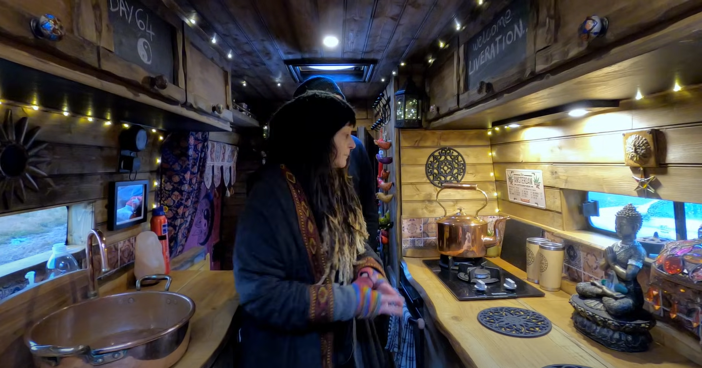 The inside of the van has a kitchen with a gas stove