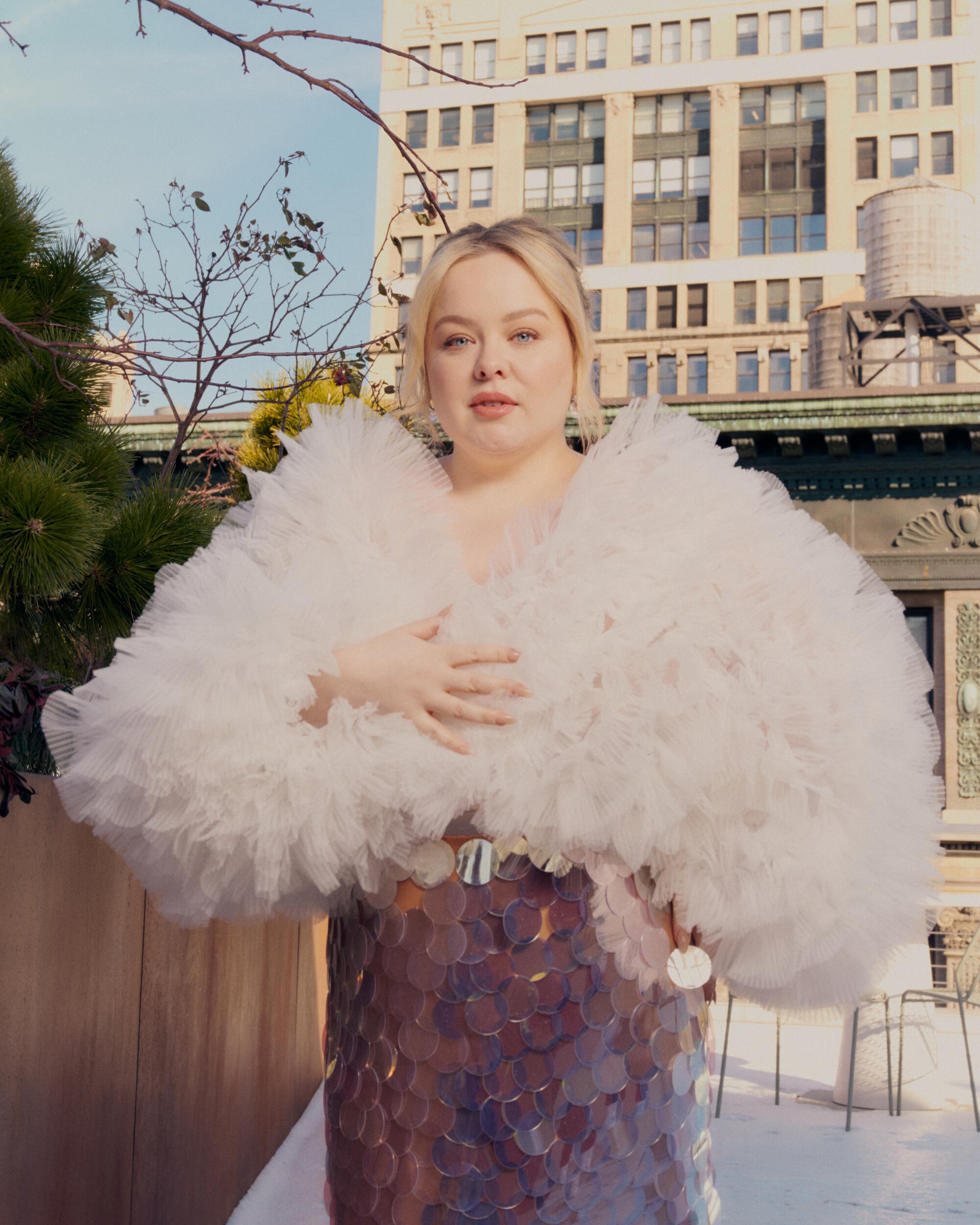 Nicola Coughlan stands outside in a puffy pink outfit.