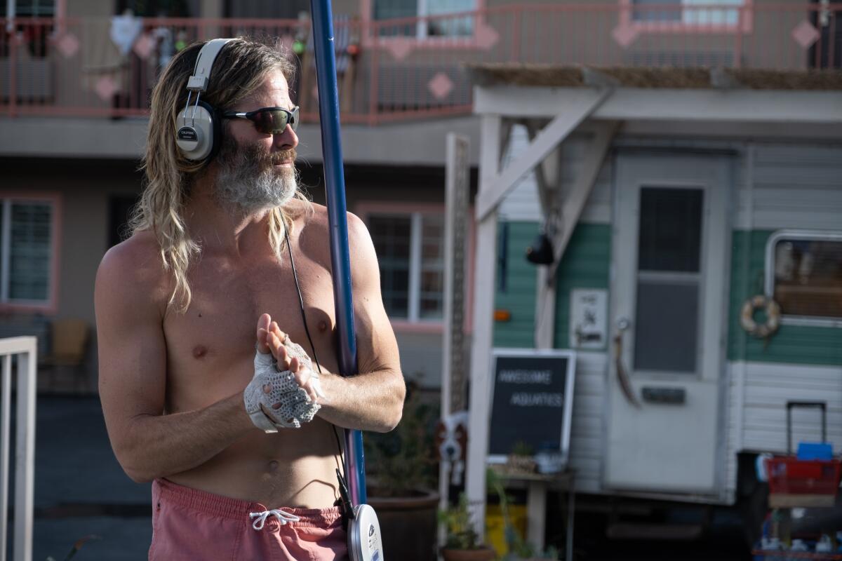 A man in headphones and shades attends to a pool.