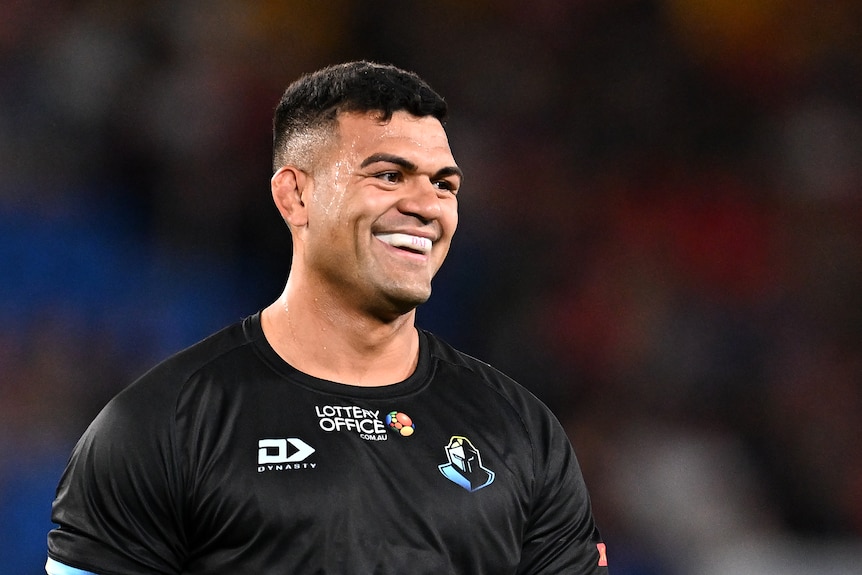 NRL player David Fifita smiles prior to a match, in a warm-up, wearing a black training shirt