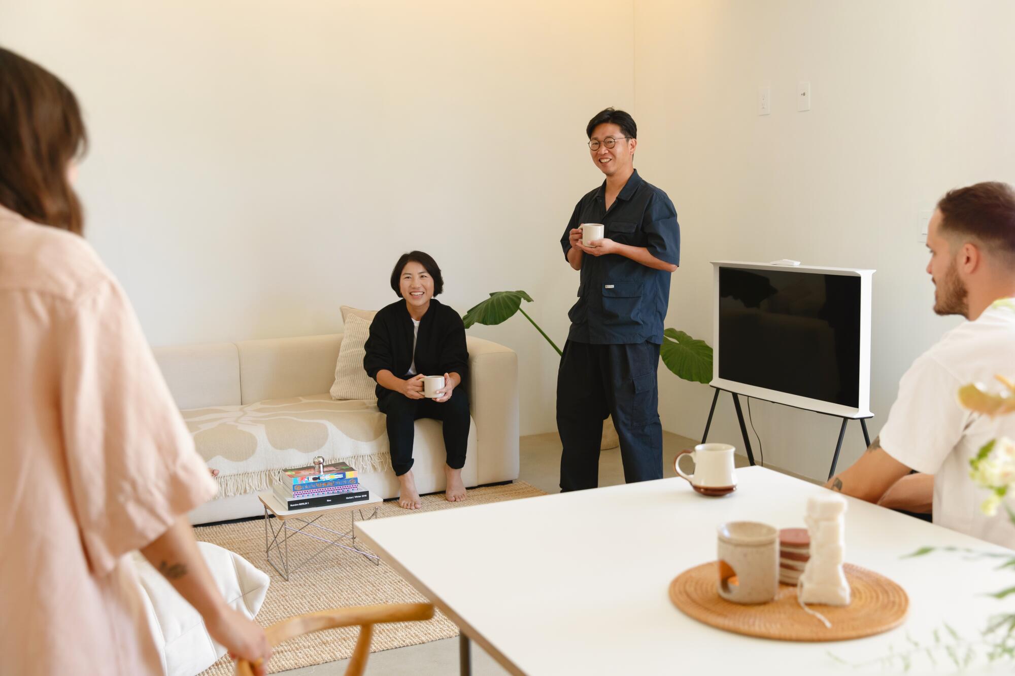 Two couples sit in a living room and enjoy coffee.