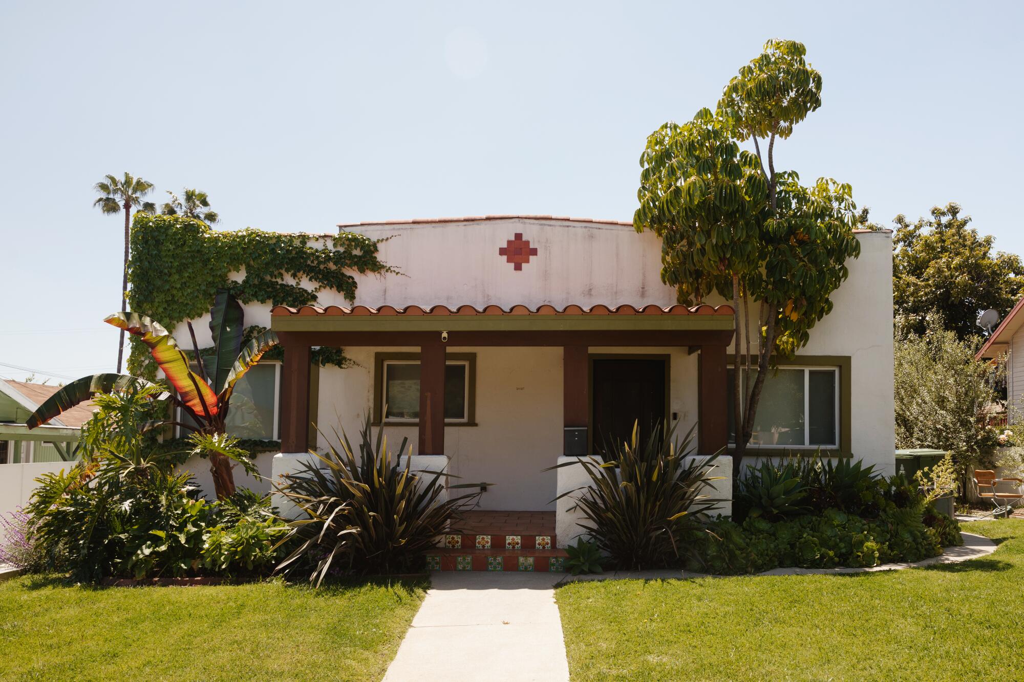 A Spanish-style bungalow fronted by a grass lawn 