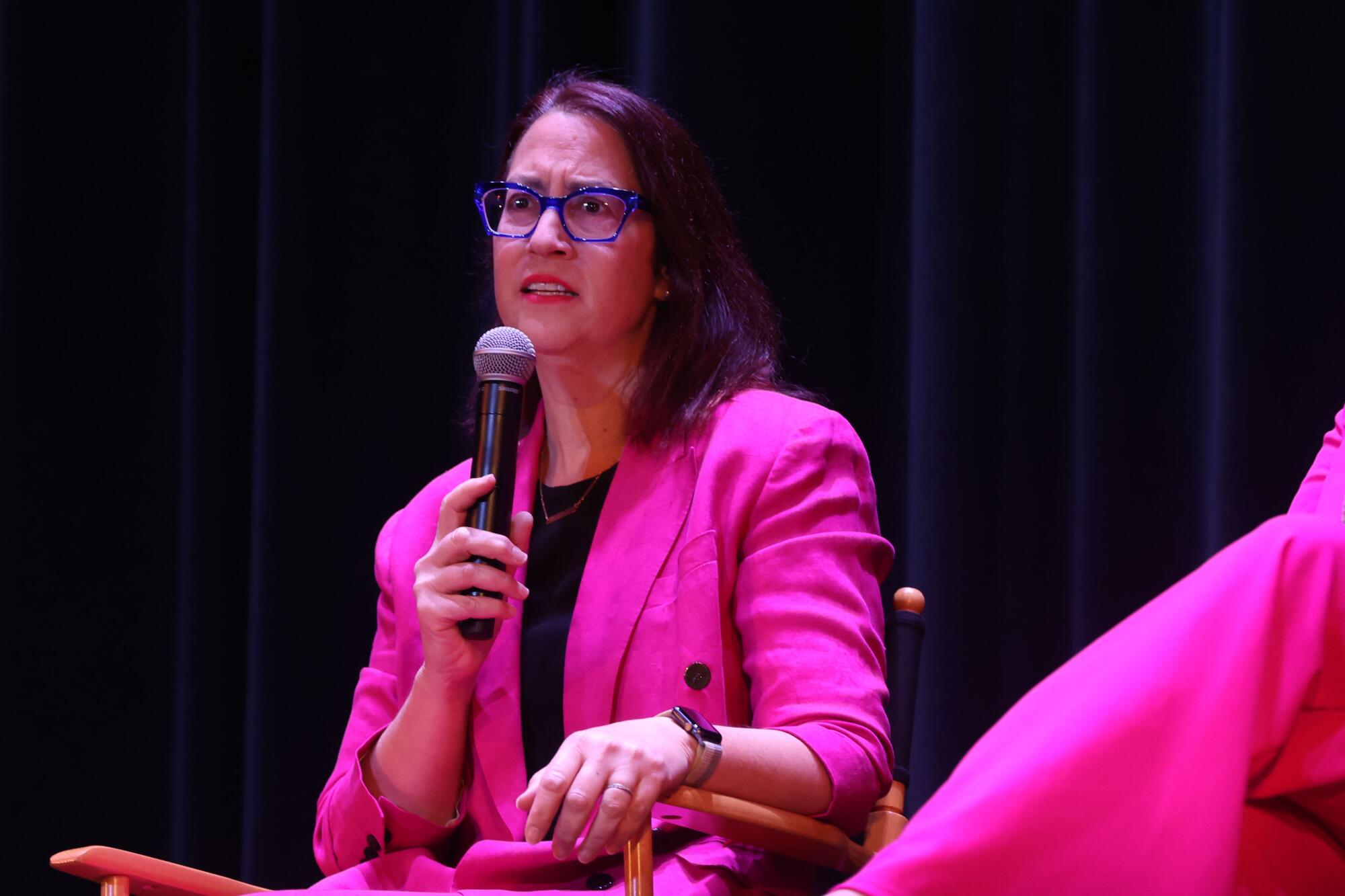 Friedman holds a microphone in a pink suit.