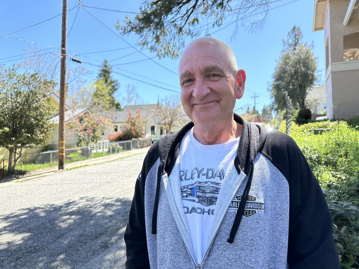 Quinn Coburn stands on a sun-dappled street in Grass Valley.