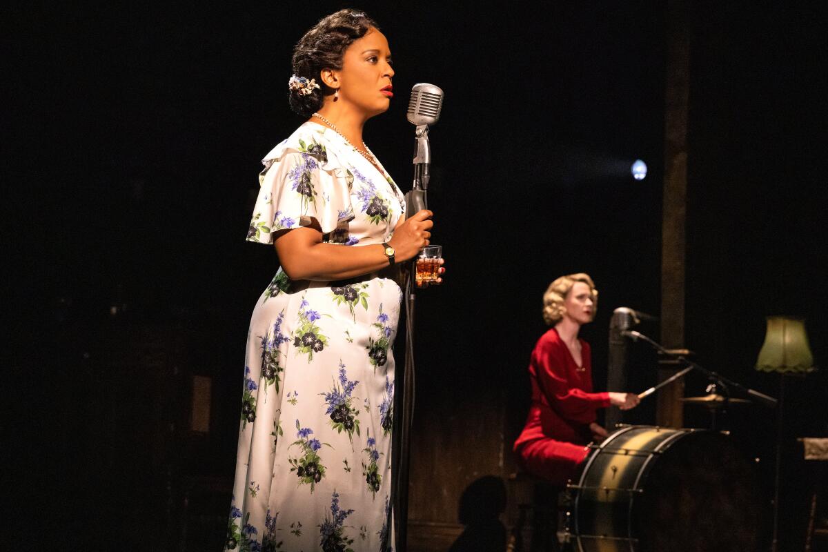 A woman stands at a microphone and sings.