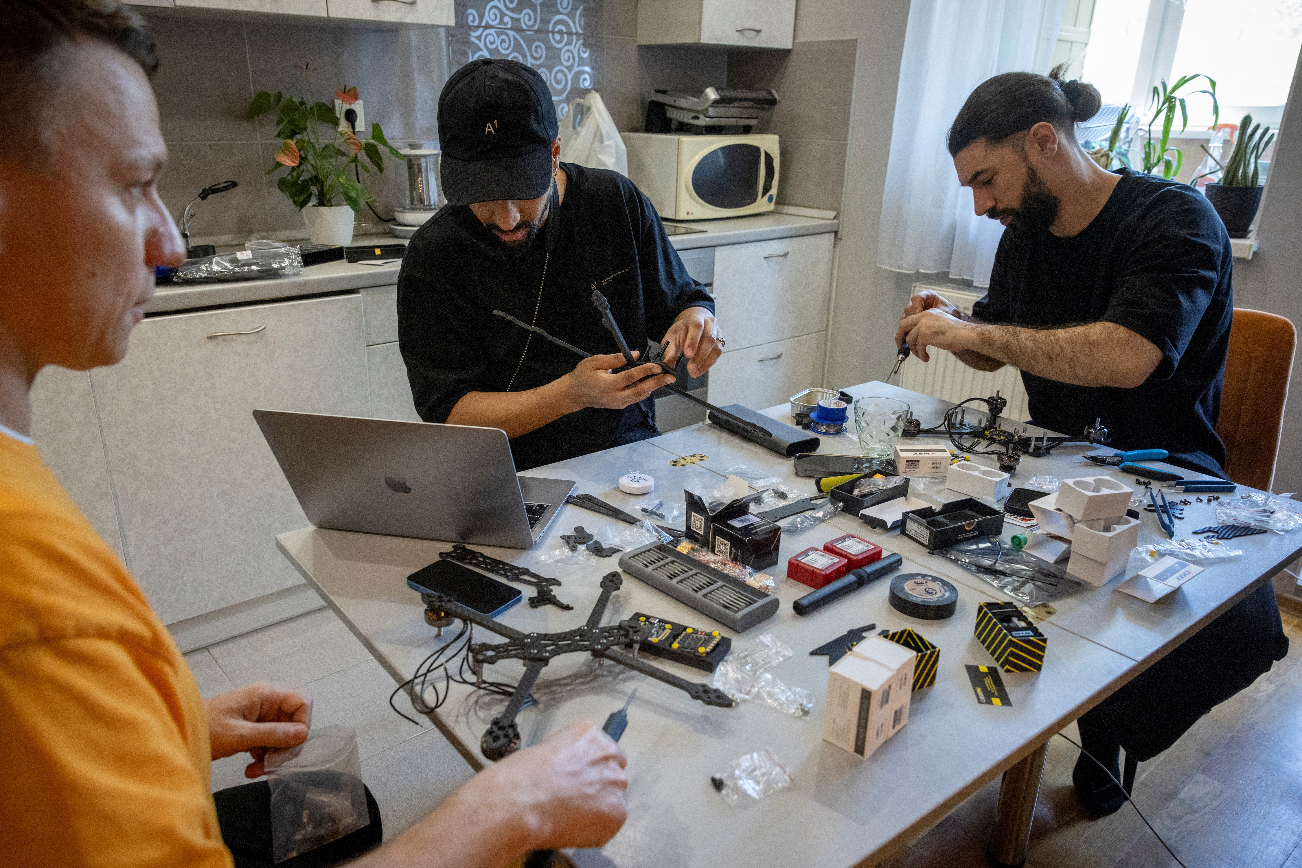 Denys, Yaw and Eugene work at their kitchen table to build drones for Ukraine's army