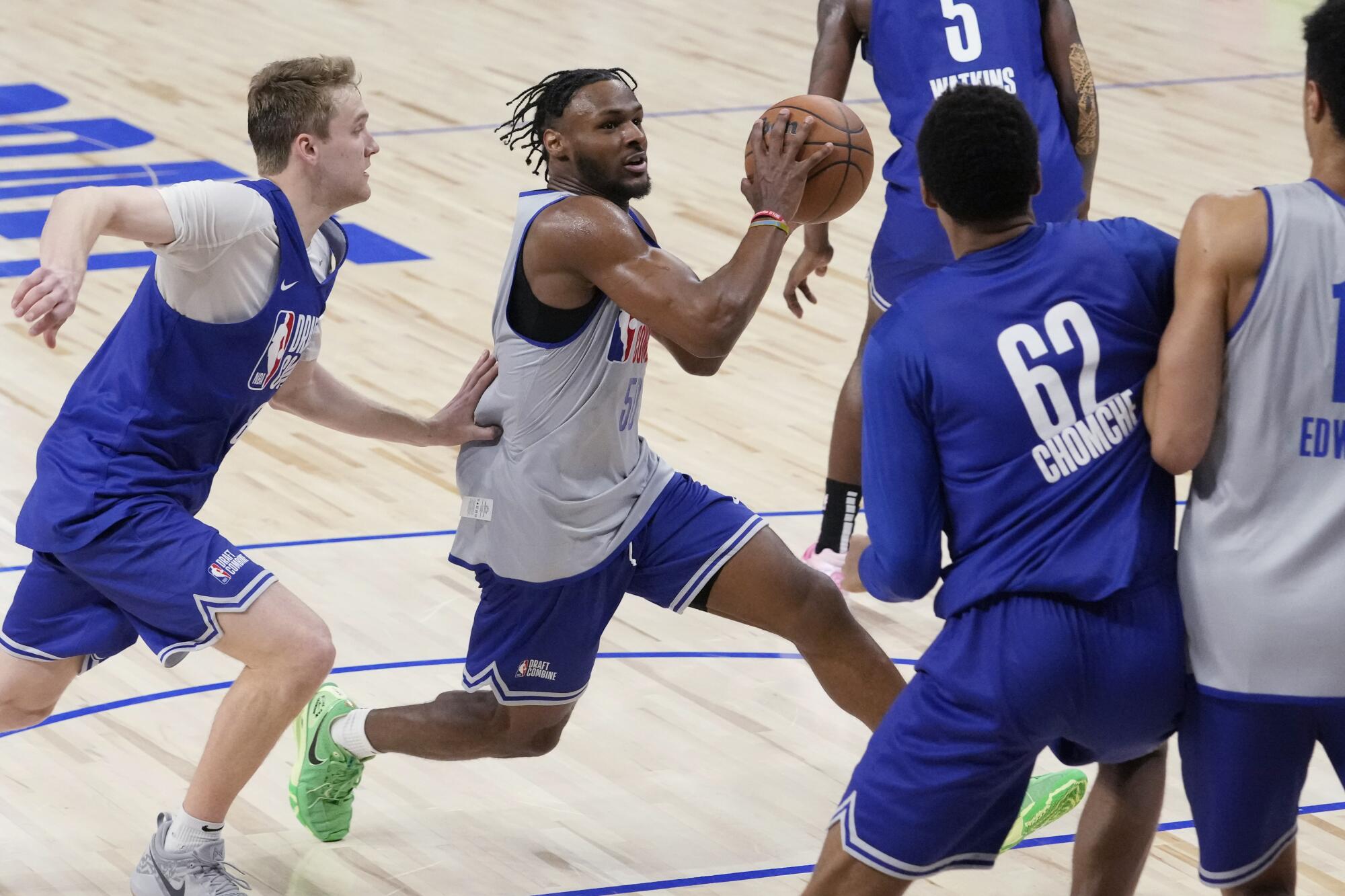 Bronny James, center, drives to the basket past Cam Spencer, left, during the NBA draft combine Tuesday in Chicago.