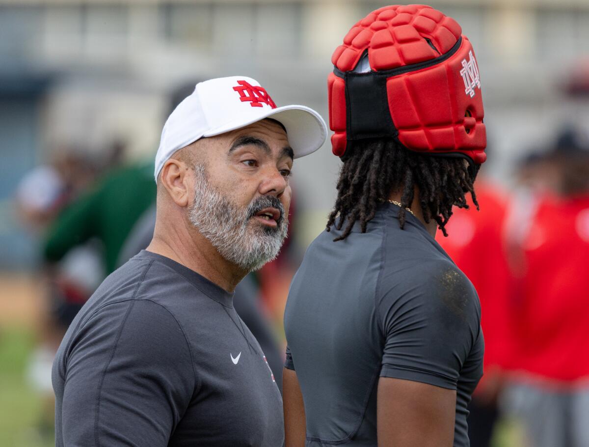 Mater Dei head coach Raul Lara talks to Mater Dei cornerback Patrick Hall.