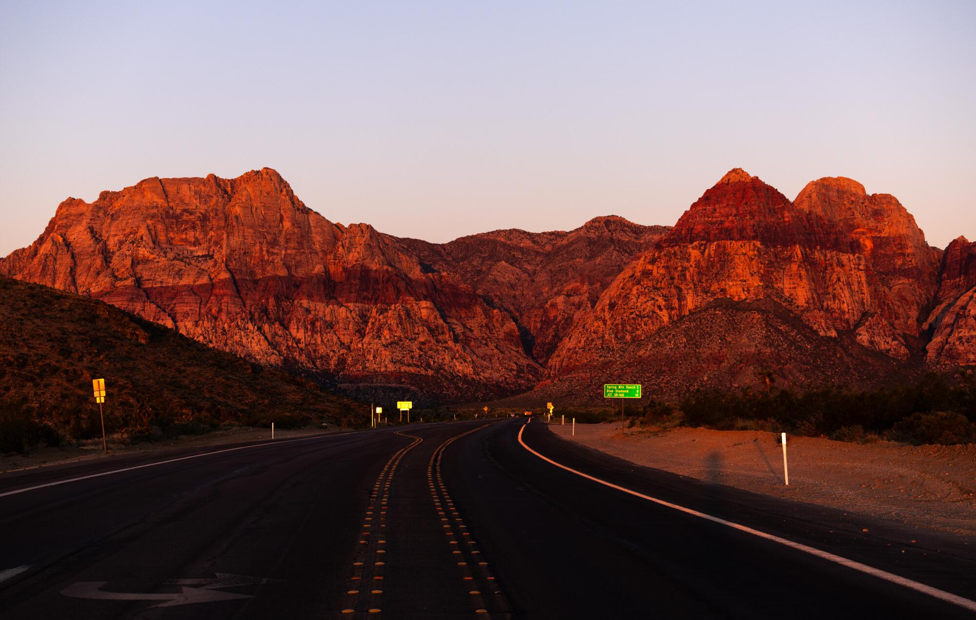 The rising sun illuminates red sandstone peaks. 