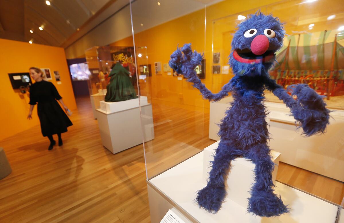 A Grover puppet on display in a glass case.