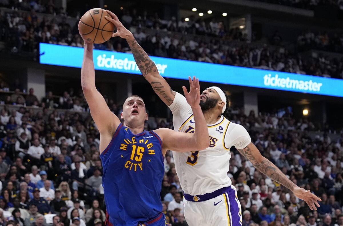 Lakers forward Anthony Davis, right, gets a hand on the ball as Nuggets center Nikola Jokic attempts a shot.