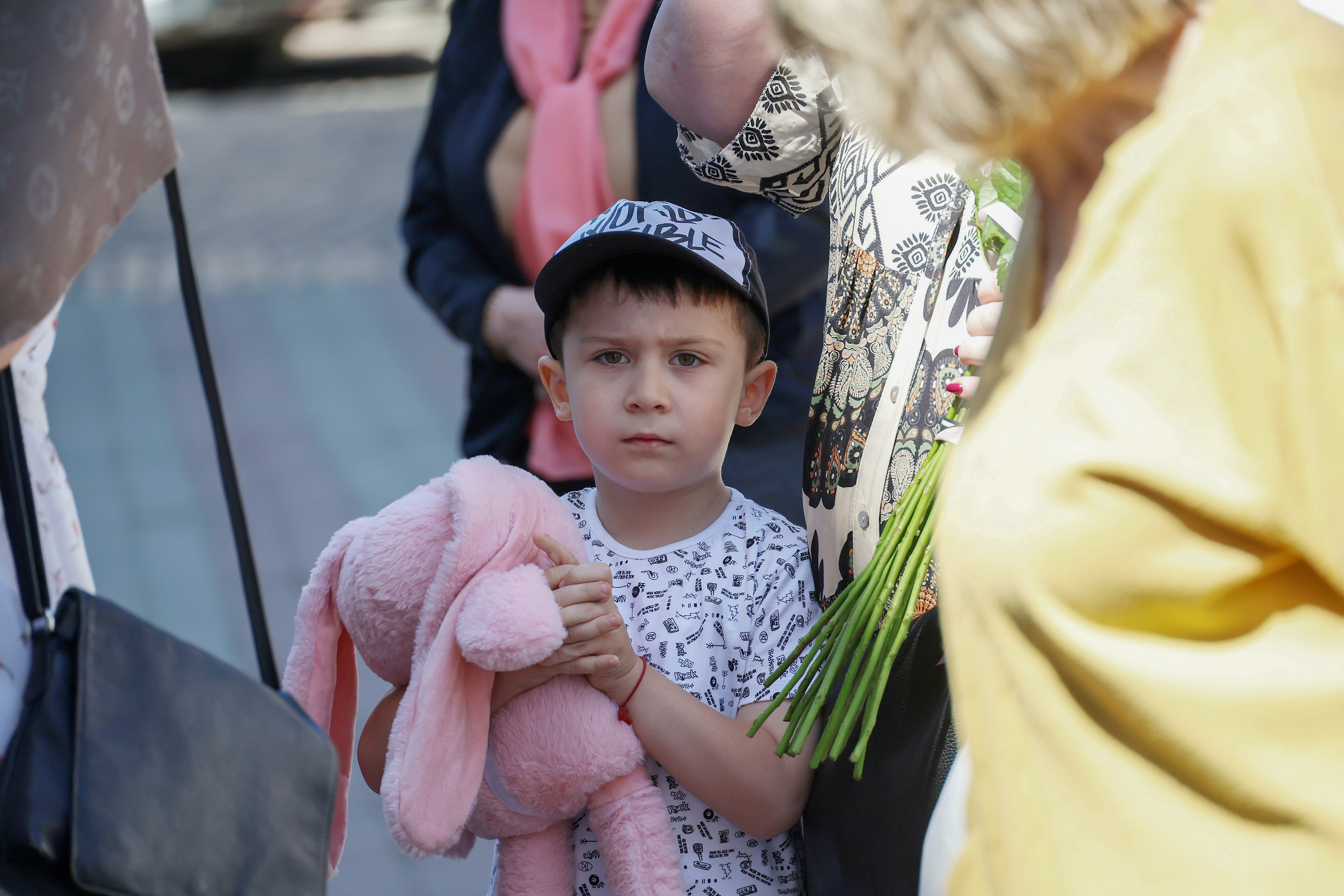 A little boy carries a pink teddy bear for the killed child