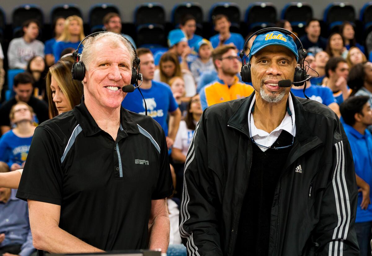 UCLA legends Bill Walton, left, and Kareem Abdul-Jabbar sit courtside during a basketball game in 2013.
