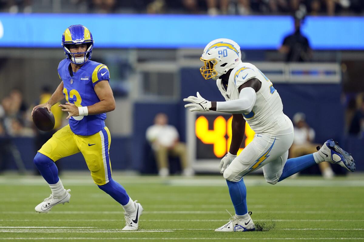 Rams quarterback Stetson Bennett (13) runs from Chargers linebacker Brevin Allen (90) in a preseason game.