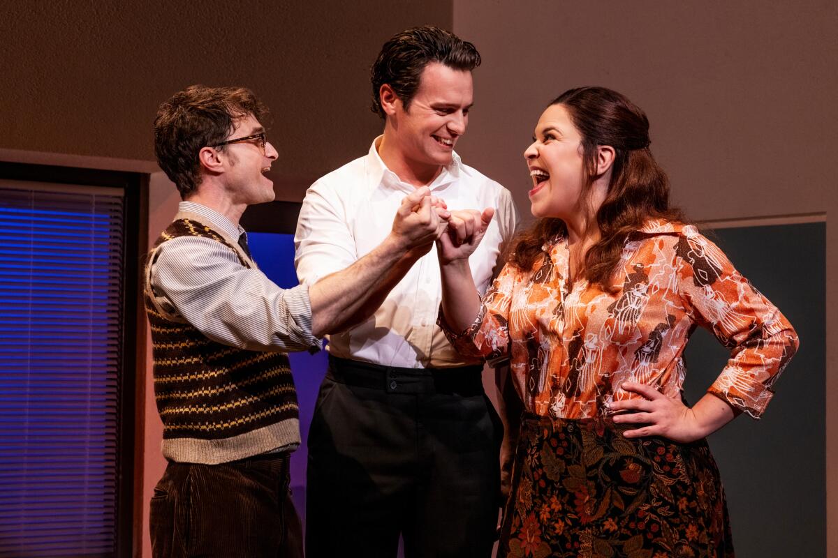 Three people stand locking pinky fingers as they sing.