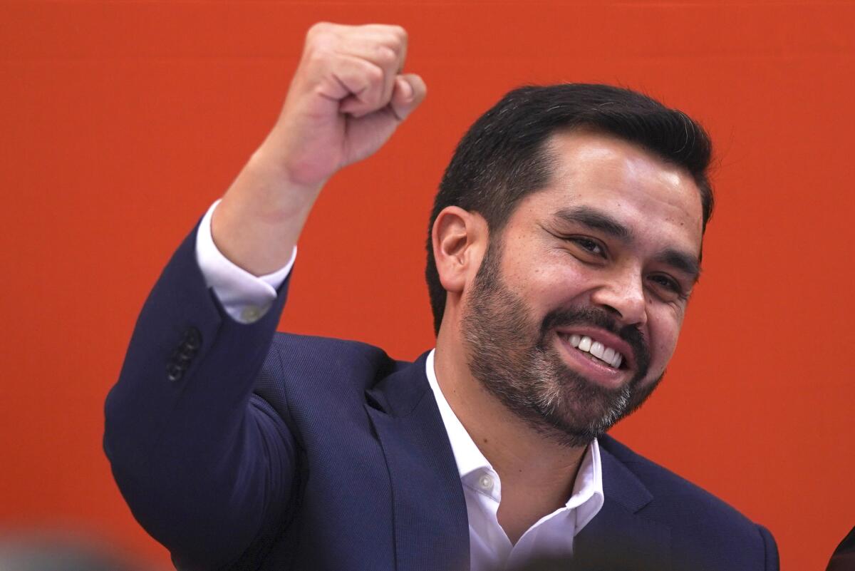  Jorge Álvarez Máynez smiles and pumps his fist against a red background.