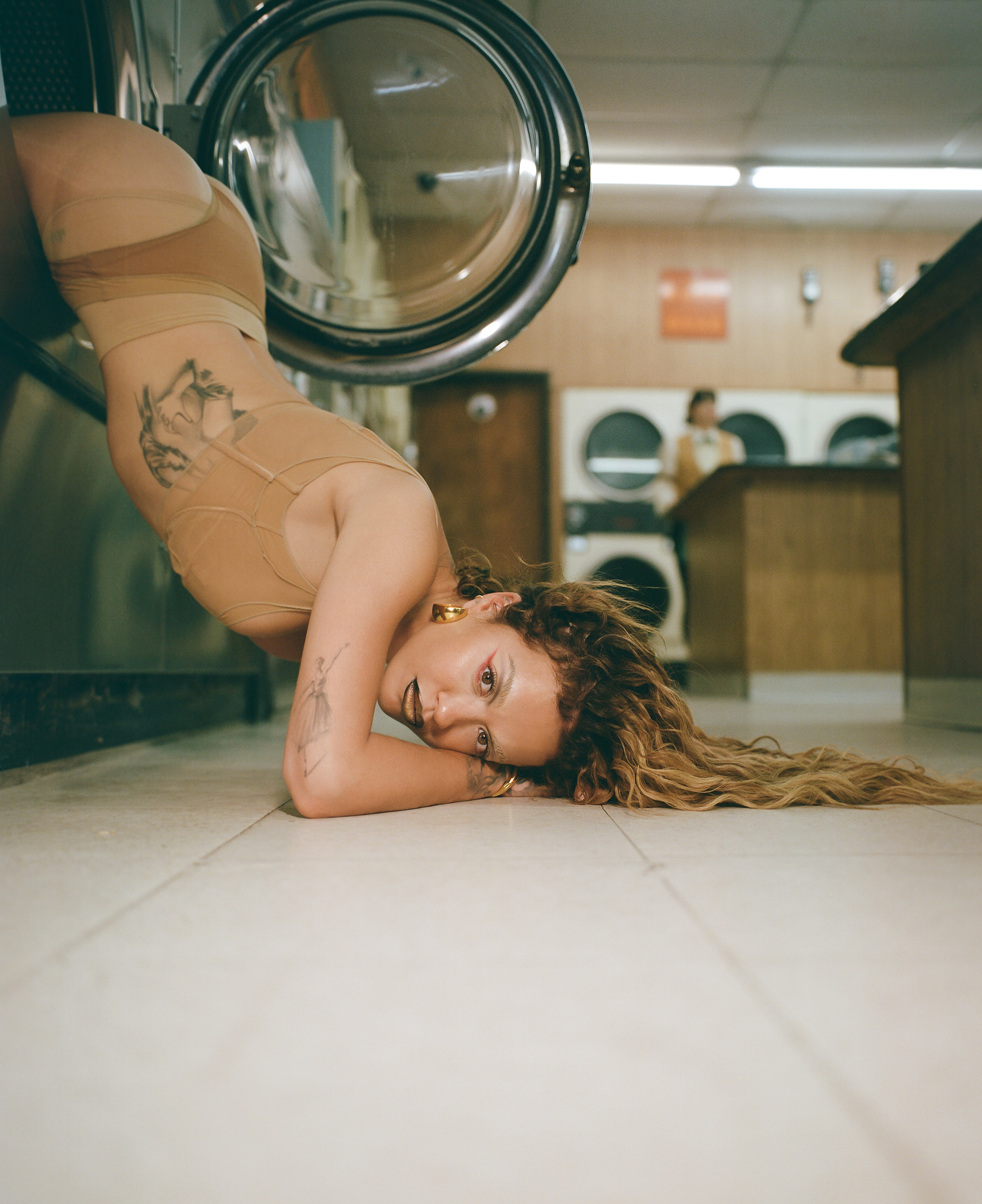 Singer Rita posed hanging out of a washing machine on the set of her music video for a track titled Ask & You Shall Receive