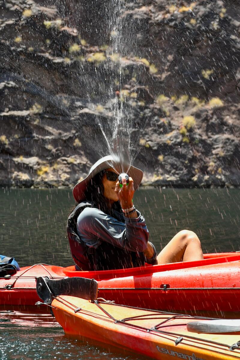 A person in an inflatable watercraft sprays water toward the camera