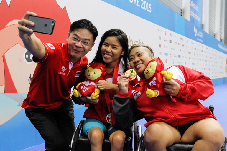 Lawrence Wong taking a selfie with two members of Singpore's team at the ASEAN Para Games in 2015. They all look happy and relaxed. 