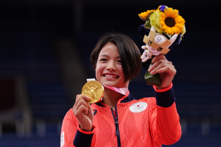 Female athlete holds Olympic medal.