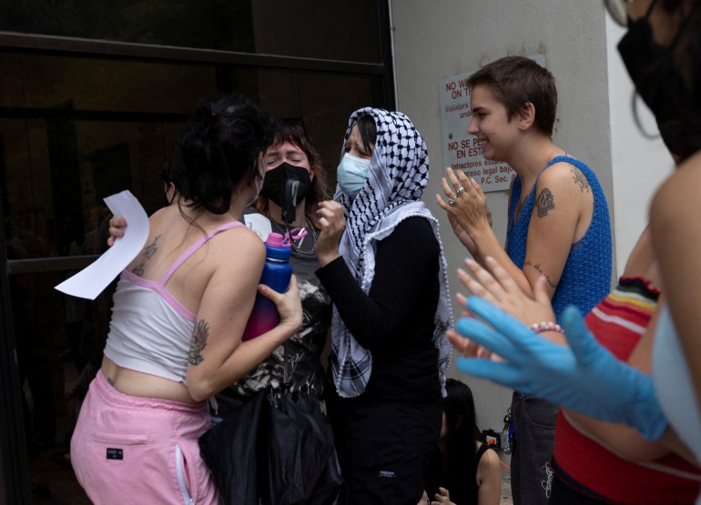 Protesters applaud one another as they exit a jail in Austin. One woman is surrounded by two friends who wrap themselves around her, as her eyes close with emotion.