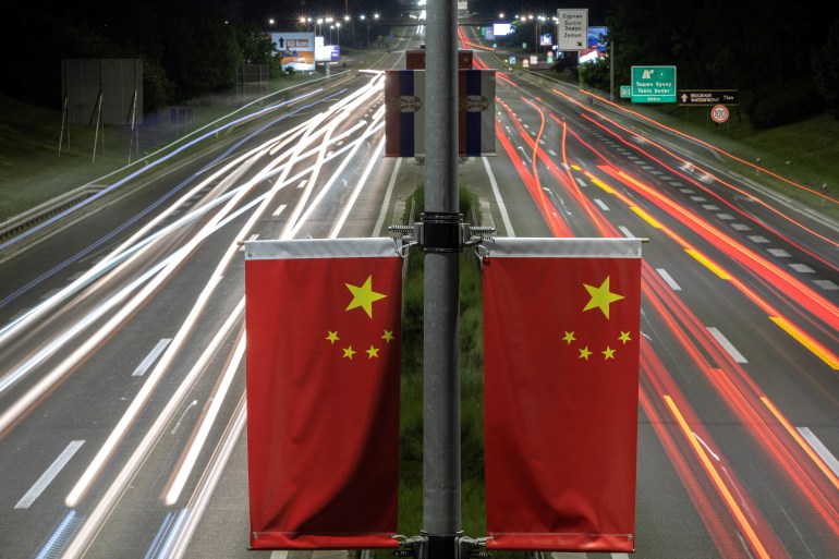 Chinese flags on the central reservation of a Belgrade road. There are white and red lines from passing cars