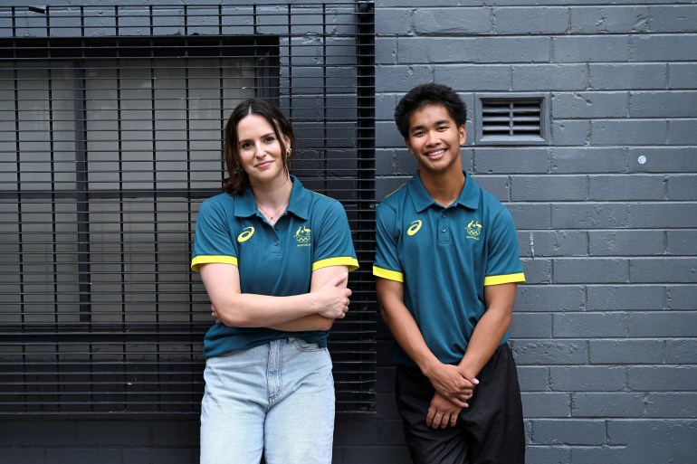 Female athlete (L) and male athlete stand up against a wall for photograph.