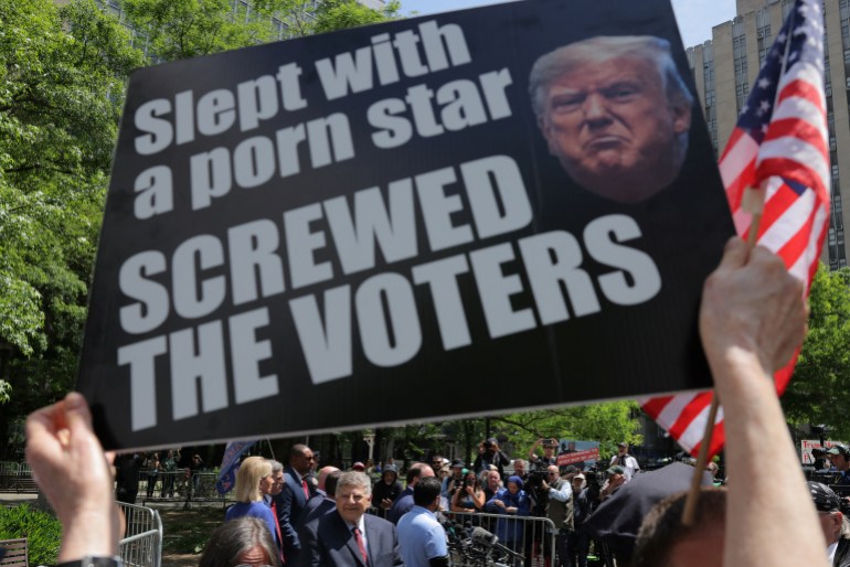 A protester in New York holds up a sign that reads, "Slept with a porn star, screwed the voters."