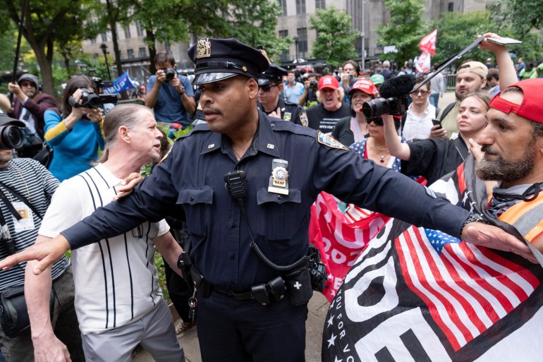 A police officer separates crowds outside the Manhattan Criminal Court