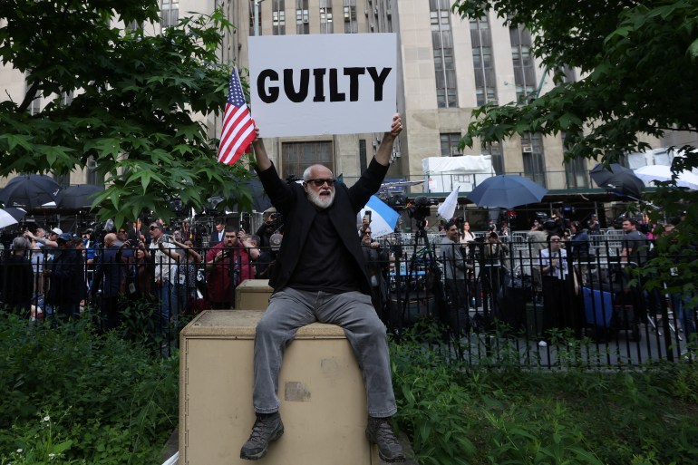 A protester holds up a sign that says "guilty"