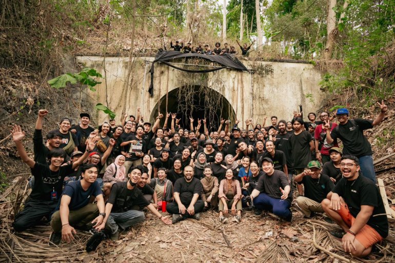 The cast and crew of Siksa Kubur. They are seated outside in front of a spooky looking archway covered in creepers.