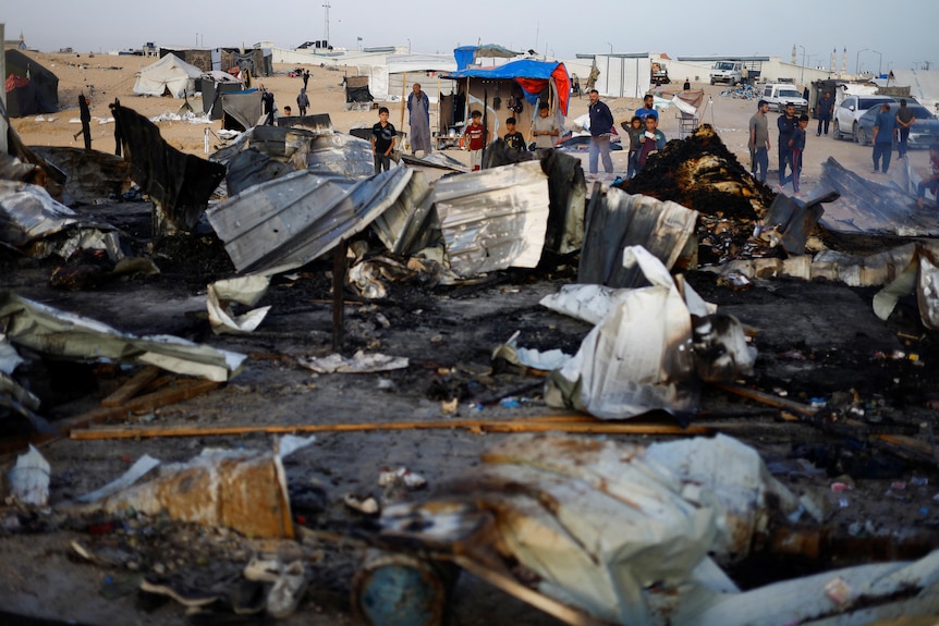 An image of debris, behind it are people looking at the damage.