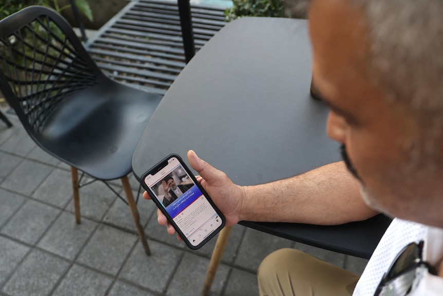 A man holds a phone showing news of the helicopter crash involving the Iranian president