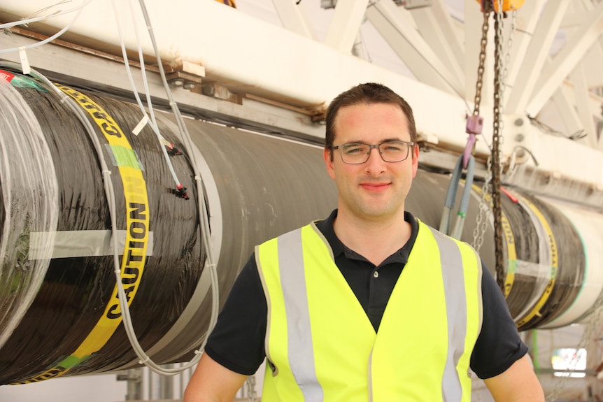 Rocket scientist in glasses and high vis vest stands in front of the rocket.