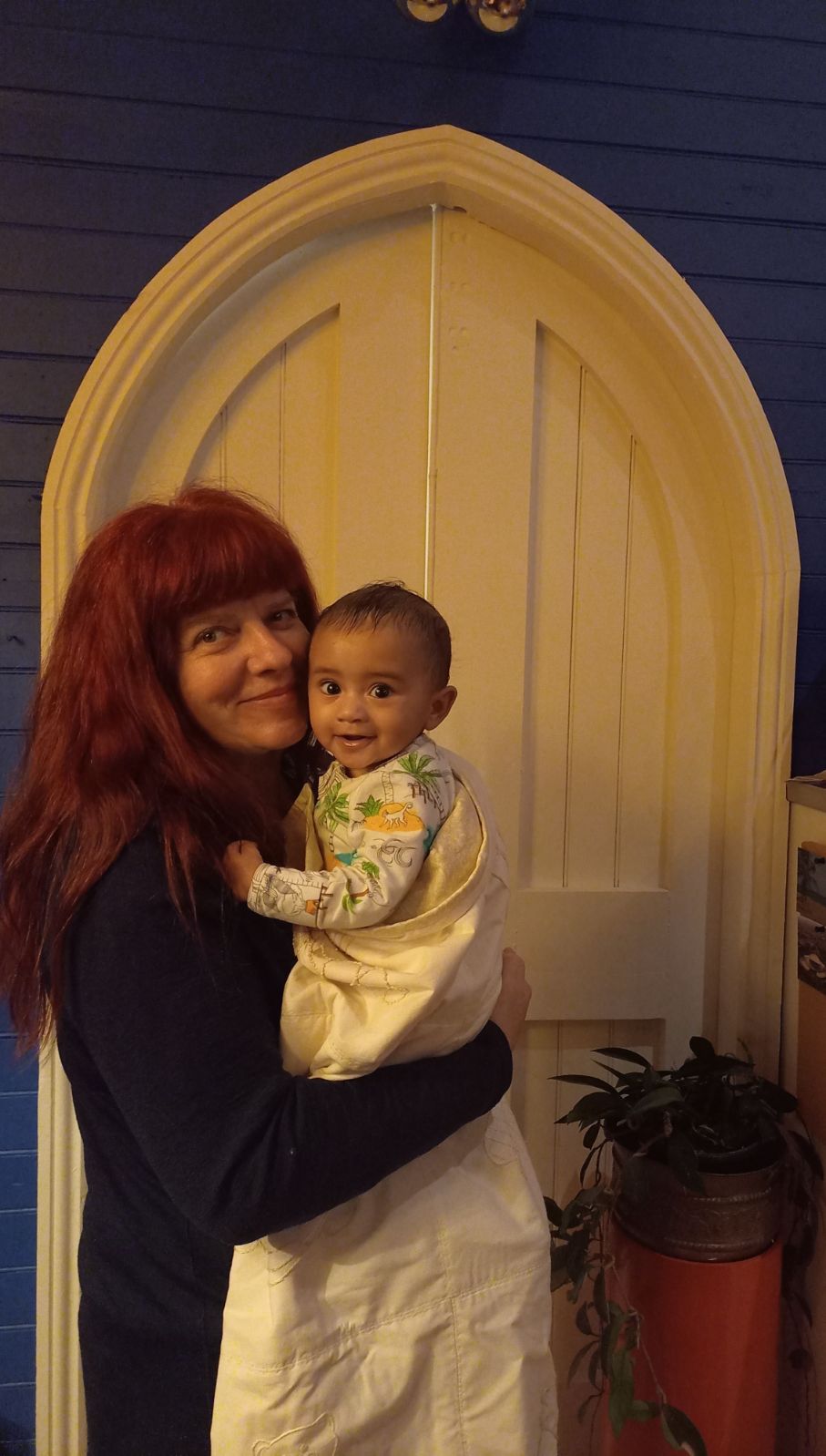Mother and baby stand in the door way of a renovate church which is set to become a family home