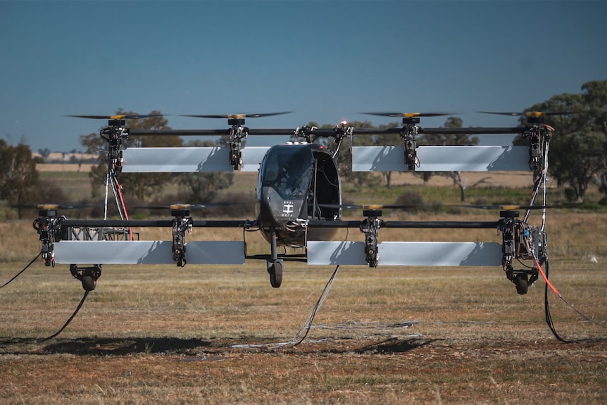 a small box wing aircraft hovers just above ground at a regional airstrip