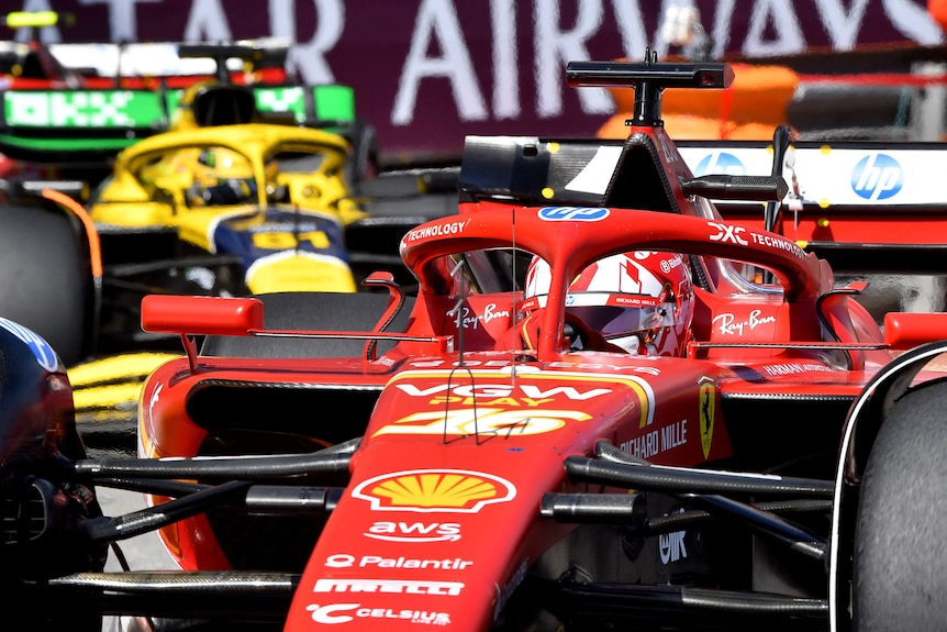 Red Ferrari leading a green and yellow McLaren through a chicane